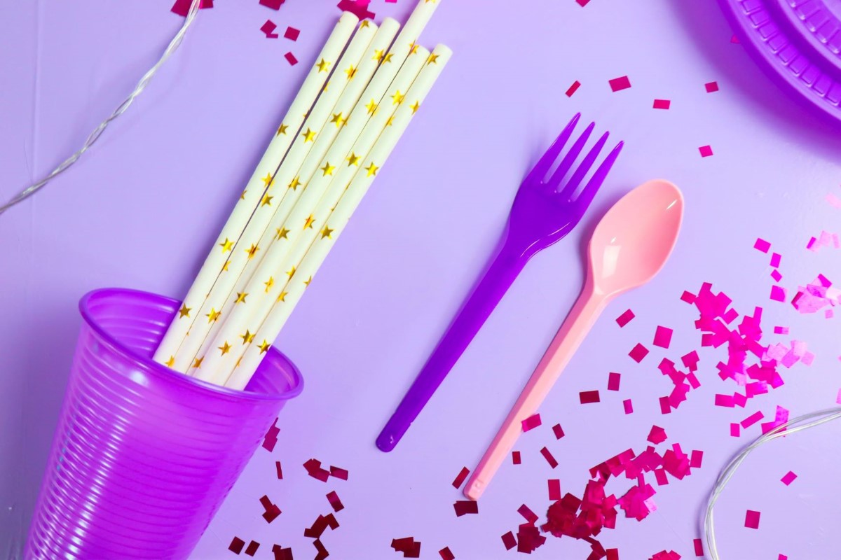 Copos, talhares e pratos descartáveis e canudos com tons de roxo e rosa. Produtos Bello Festas.